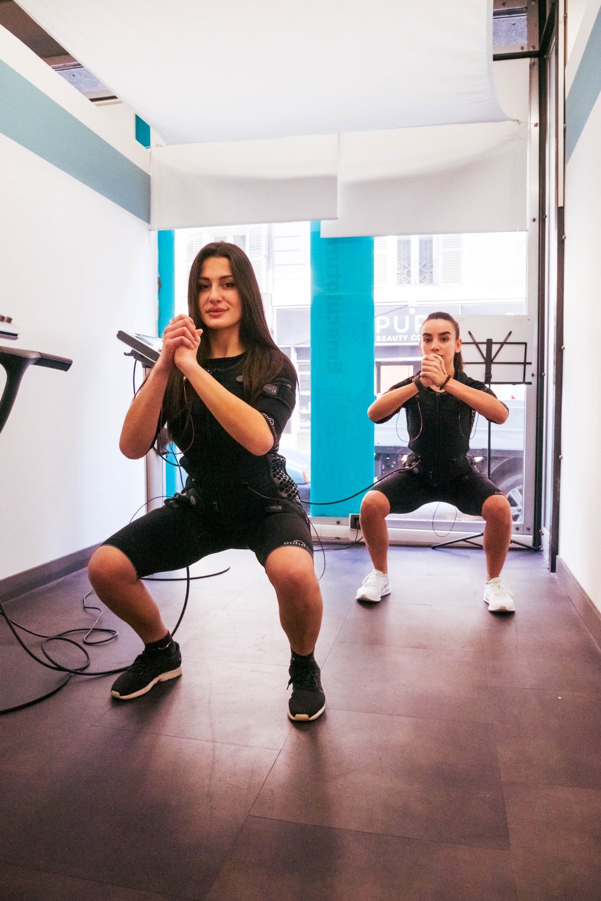 Due persone in tuta per elettrostimolazione durante una seduta Bodytec.