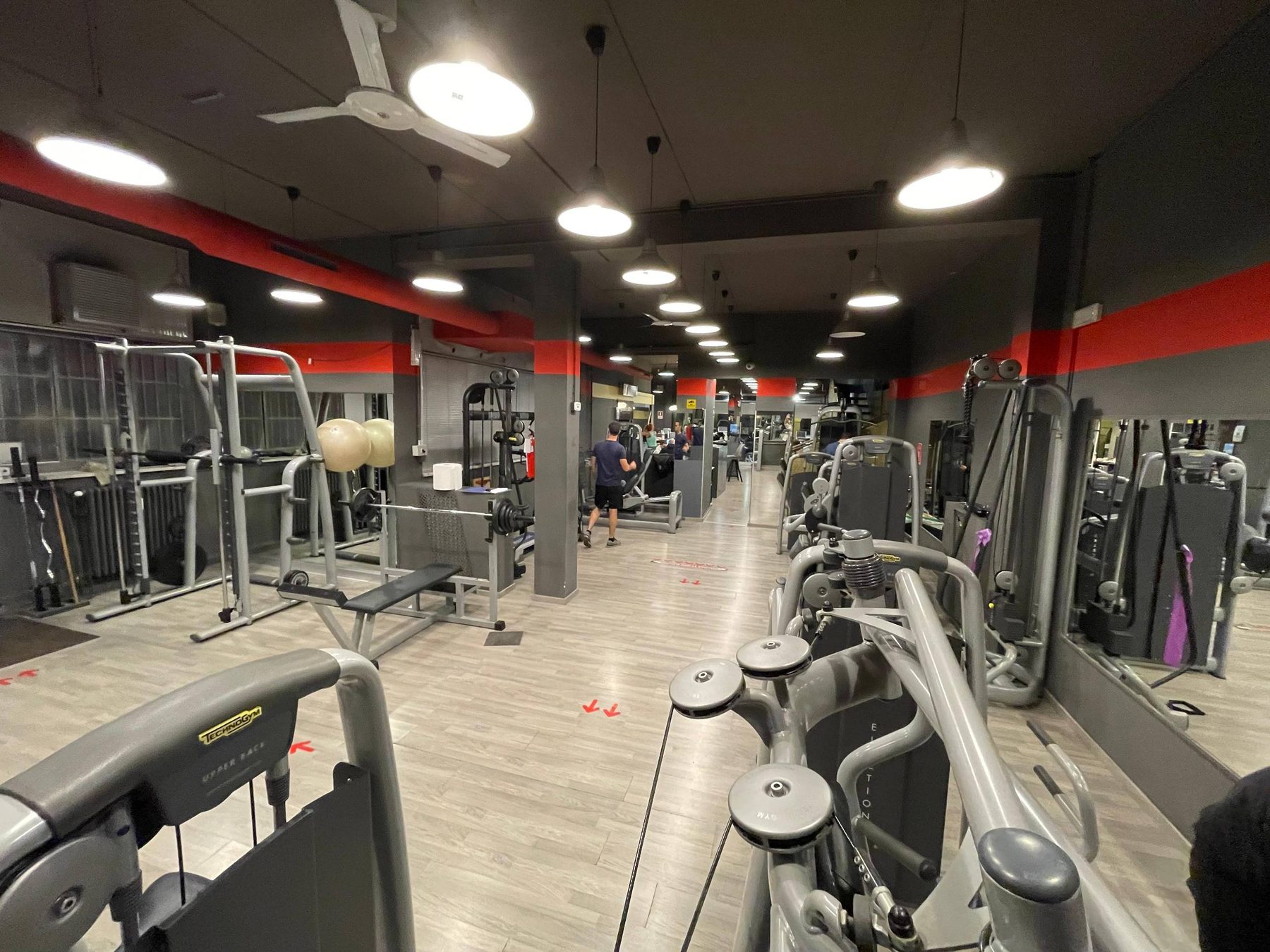 La sala pesi di Ginnic Life con le macchine Technogym allineate sotto la fascia rossa.